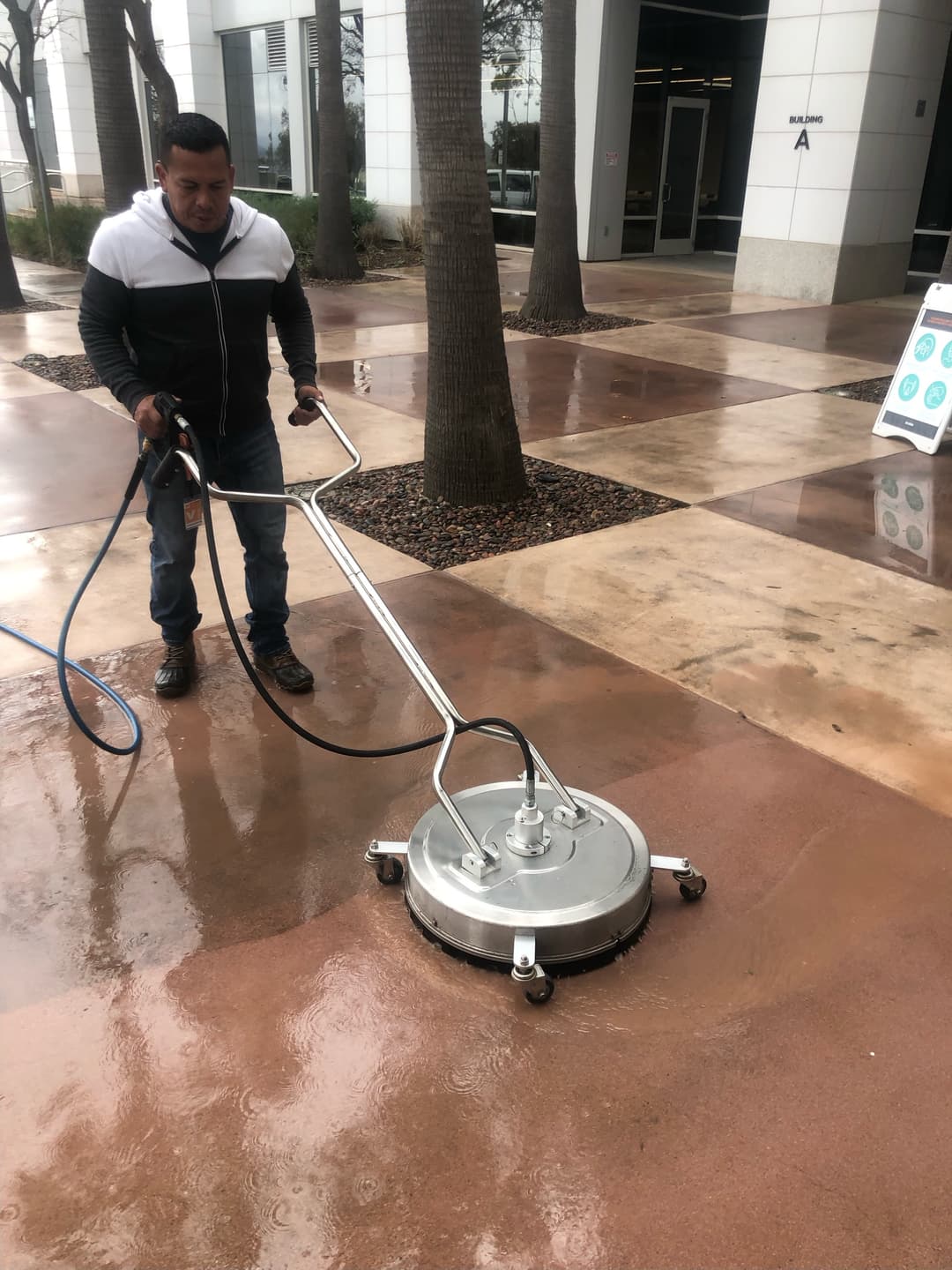 Man pressure washing a concrete sidewalk