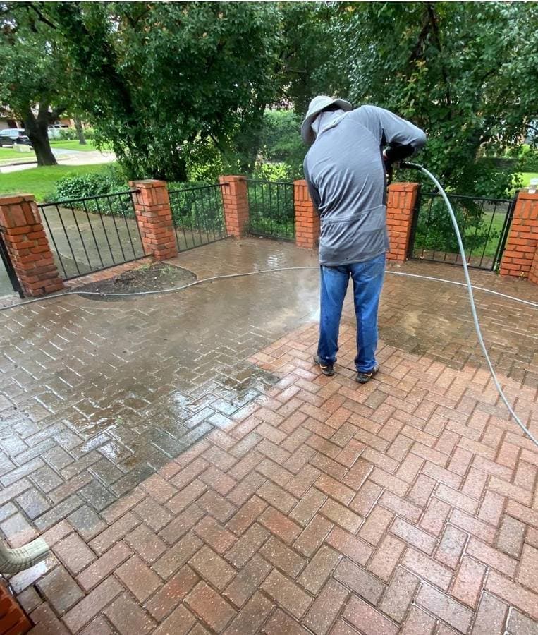 Man pressure washing pavers