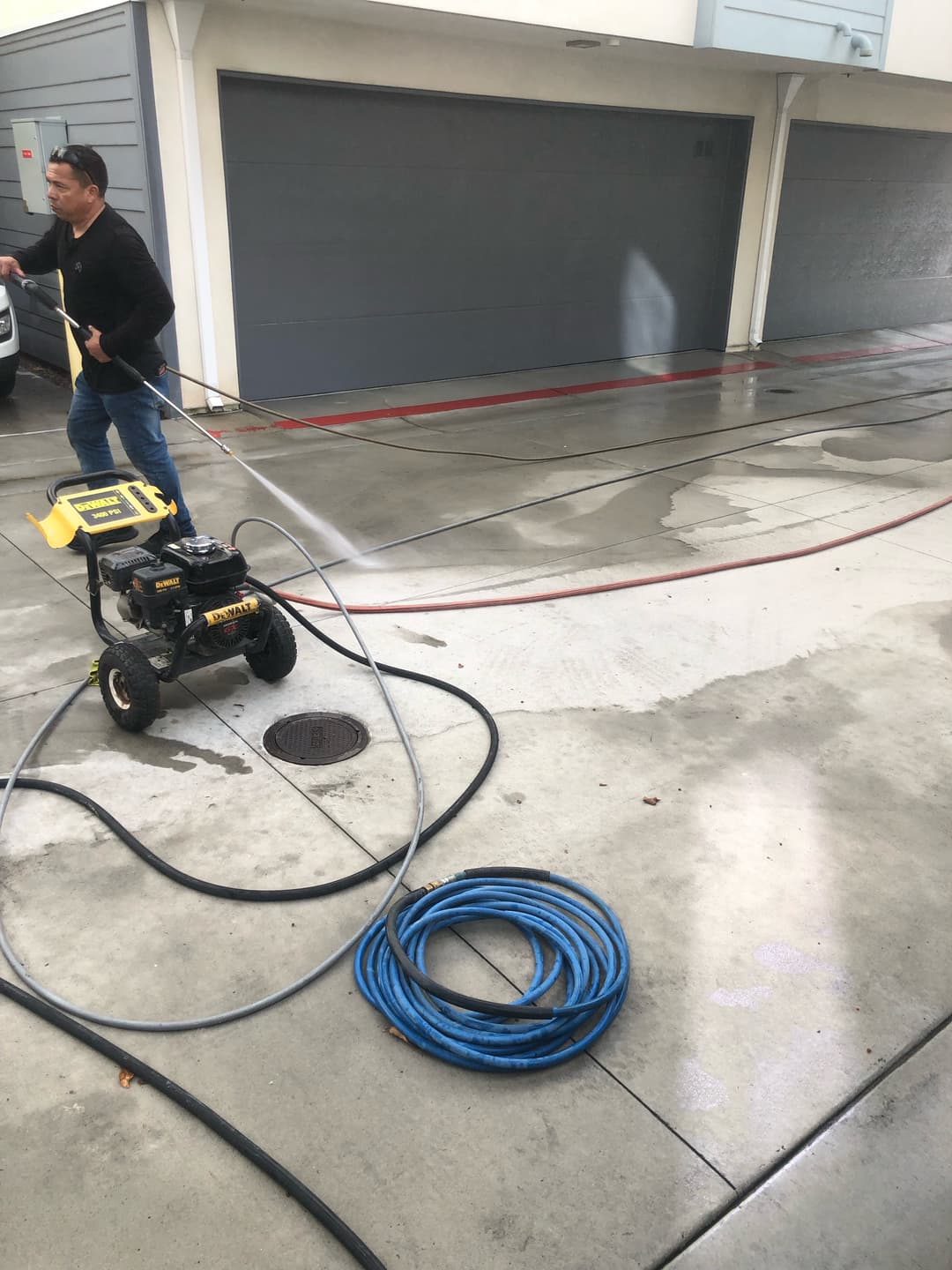 Man power washing a garage driveway